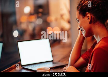 Smiling woman working on laptop while sitting at cafe Stock Photo