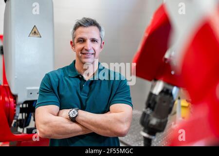 Smiling man with arms crossed standing in factory Stock Photo