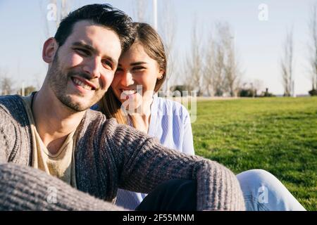 Smiling couple sitting together in park Stock Photo