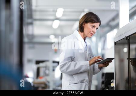 Mature female technician using digital tablet at laboratory Stock Photo