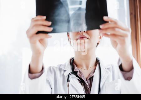 Female medical professional examining x-ray image against window Stock Photo