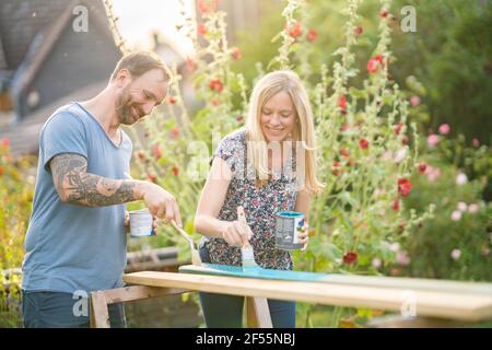 Couple painting wooden plank in garden Stock Photo
