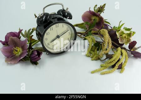 Vintage clock with spring flowers. Daylight saving time concept. Stock Photo