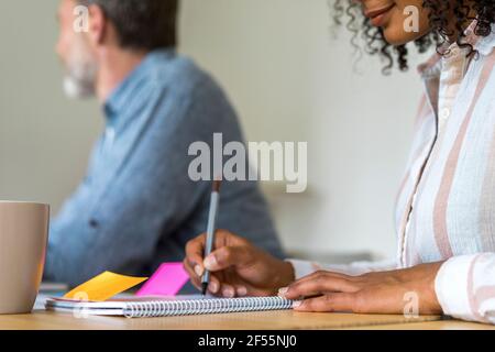 Young female entrepreneur writing notes in diary during meeting at office Stock Photo