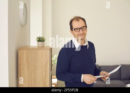 Portrait of a senior businessman standing with documents in his hands and looking at the camera. Stock Photo