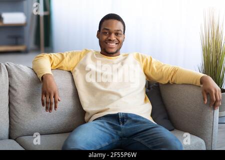 Handsome black man sitting on sofa at home Stock Photo