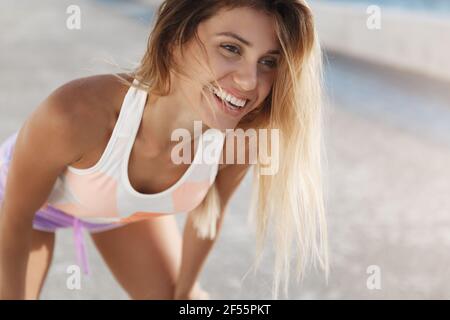 Happy sporty fitness woman satisfied good productive training session, enjoying test body strengths performing long-run, smiling, gasping tired after Stock Photo