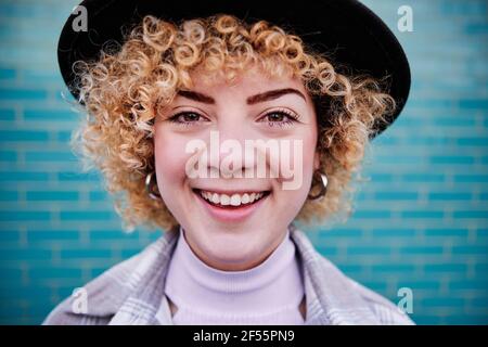 Smiling curly haired woman in hat Stock Photo