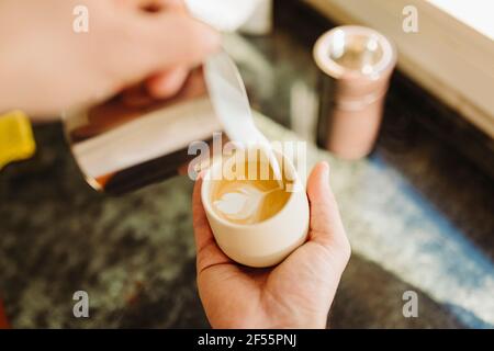 Young man preparing latte in kitchen Stock Photo