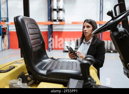 Confident female manager using digital tablet at illuminated warehouse Stock Photo
