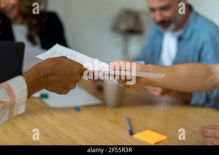Coworkers giving document to each other at during meeting in office Stock Photo