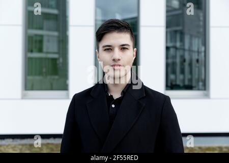 Young businessman standing against office building Stock Photo