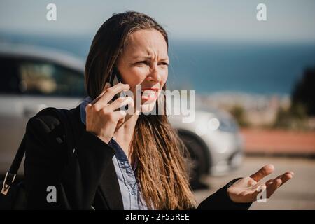 Angry businesswoman talking on mobile phone during sunny day Stock Photo