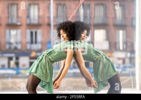 Afro young woman leaning against glass wall in city Stock Photo