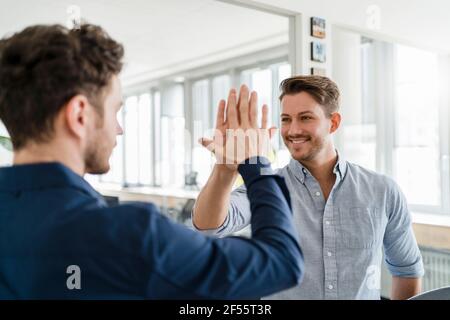 Smiling business man doing high-five with male colleague in office Stock Photo