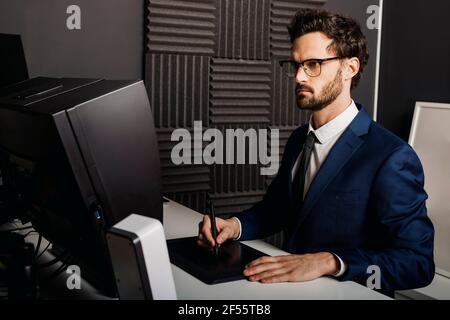 Businessman using graphic tablet at desk in office Stock Photo