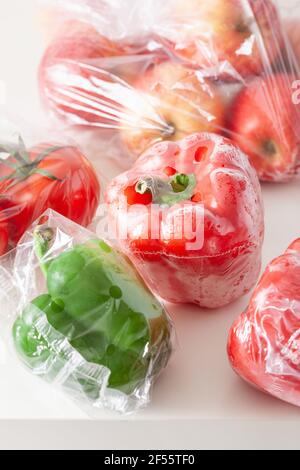 single use plastic packaging issue. peppers tomatoes apples vegetables in plastic bags Stock Photo