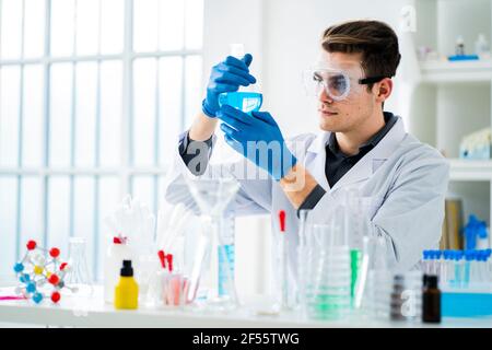 Young scientist measuring chemical in flask at laboratory Stock Photo