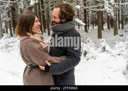 Young couple smiling while standing together in forest Stock Photo