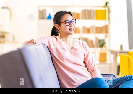 Thoughtful woman sitting on sofa at home Stock Photo
