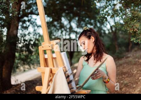 Young woman artist painting on easel Stock Photo