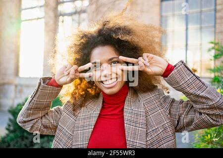 Happy young woman gesturing while standing against building Stock Photo