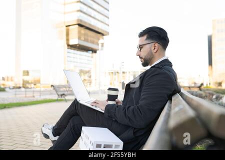 Male architect using laptop while sitting on bench in city Stock Photo