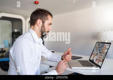 Entrepreneur having discussion with team on video conference over laptop at office Stock Photo