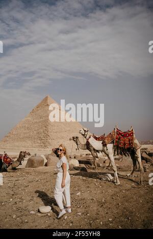 Female tourist looking over shoulder at camera in front of Great Pyramid of Giza Stock Photo