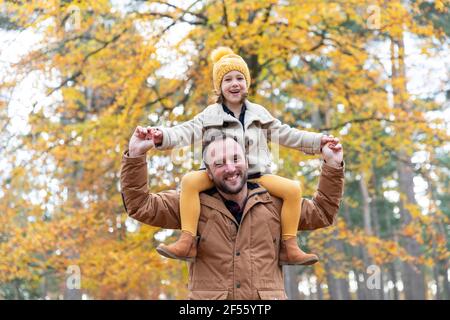 Playful father carrying smiling daughter while standing in forest