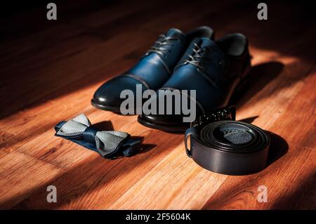 Blue leather men's shoes, bow tie and belt lie on the floor. Groom's accessories Stock Photo