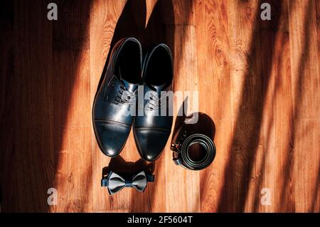 Blue leather men's shoes, bow tie and belt lie on the floor. Groom's accessories Stock Photo