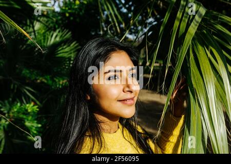 Beautiful smiling woman looking away by tree in park Stock Photo