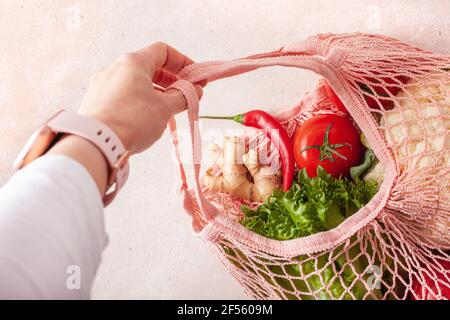 hand holding fruits vegetables in reusable mesh cotton bag, plastic free zero waste concept Stock Photo