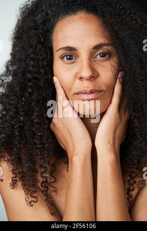 Serious curly haired woman touching face Stock Photo