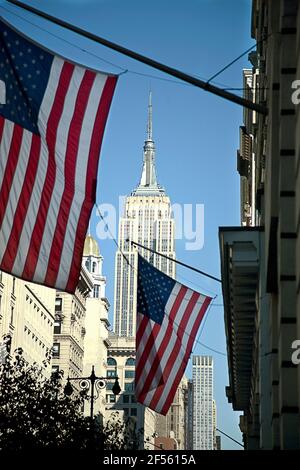 USA, New York, New York City, American flags hanging against Empire State Building Stock Photo