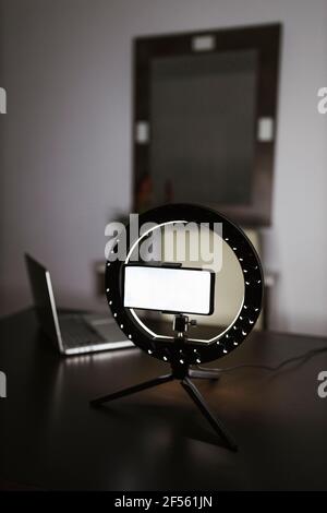 Smart phone with LED ring light and laptop on table in darkroom Stock Photo