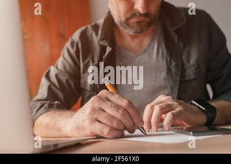 Close-up male hands writing in notebook with pen make notes information ...