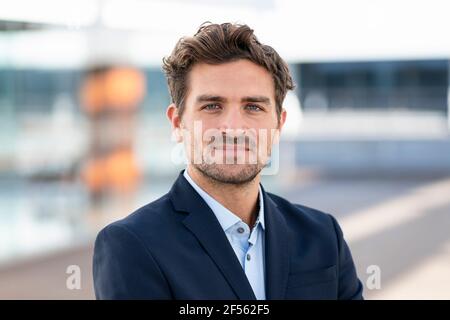 Smiling businessman staring while standing outdoors Stock Photo