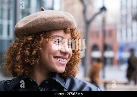 Smiling teenage girl wearing beret looking away while standing outdoors Stock Photo