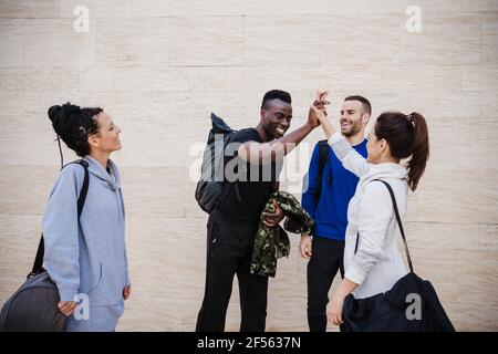 Happy male and female athlete giving high-five while standing by wall Stock Photo