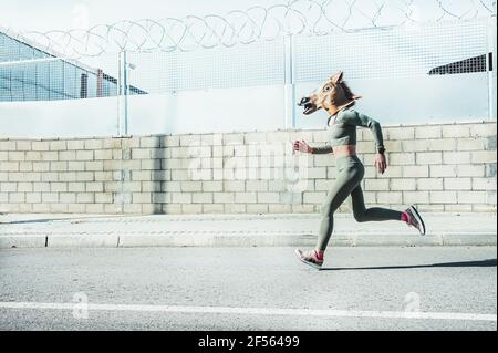 Mature woman in horse mask running on road Stock Photo