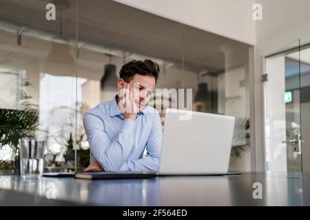 Thoughtful businessman working on laptop at office Stock Photo