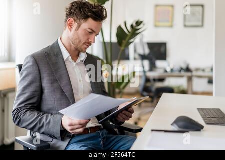 Male entrepreneur working on document and digital tablet at office Stock Photo