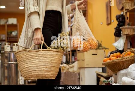 Herbs and Orange fruit in bag held by woman at store Stock Photo