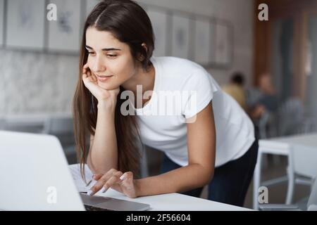 Beautiful caucasian woman using laptop computer smiling searching for information on internet in public library. Stock Photo