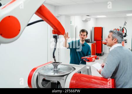Male engineers discussing over machinery in industry Stock Photo