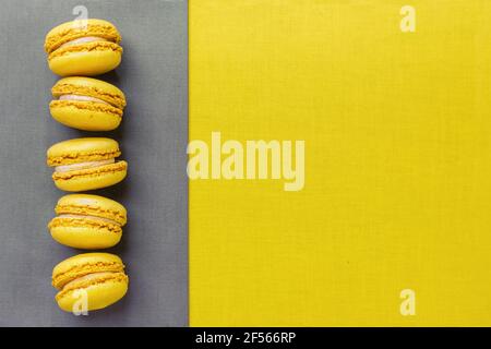 Trendy Color of the Year 2021. Illuminating Yellow and Ultimate Gray. Yellow macaroons on gray background, flat lay. Stock Photo