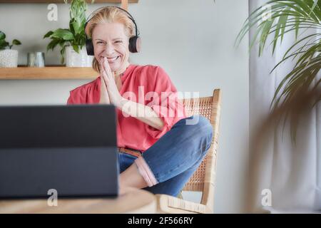 Smiling woman greeting during video call on laptop at home Stock Photo