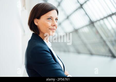 Mature businesswoman looking away in corridor Stock Photo